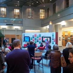 Un photo d'une foule qui &eacute;coutant une pr&eacute;sentatrice qui est debout devant un panneau du Hub.